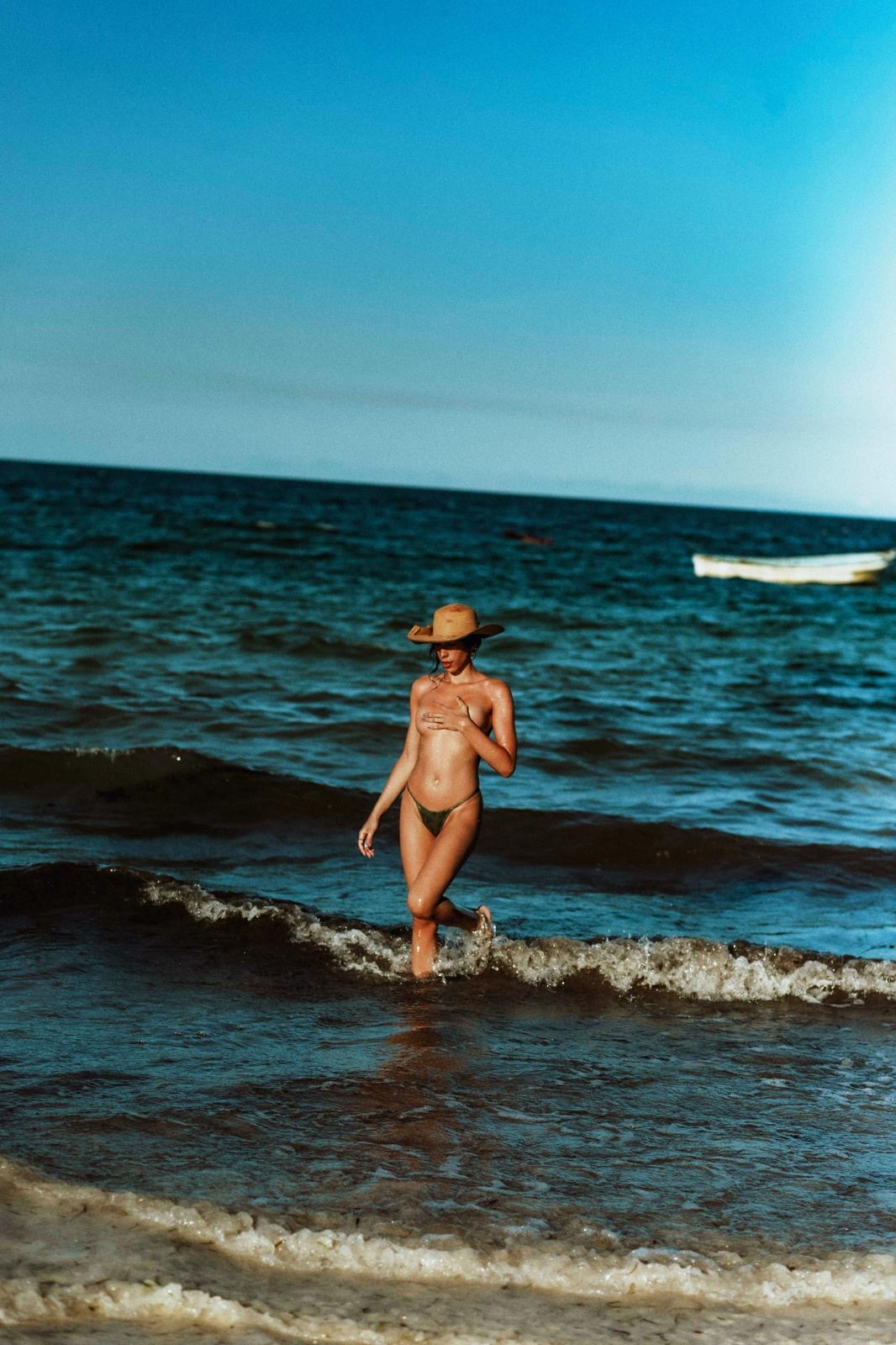 Olivia marchant dans la mer avec un chapeau de soleil.